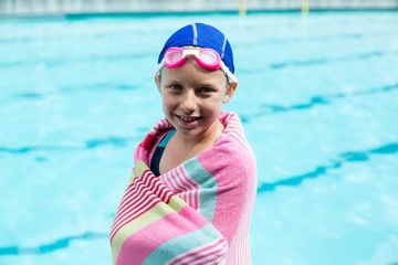 Girl wrapped in towel standing at poolside