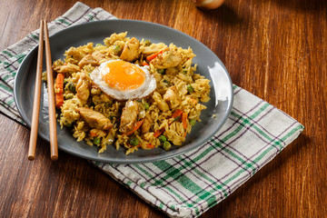 Fried rice nasi goreng with chicken egg and vegetables on a plate.