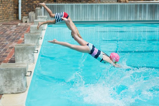Children diving in water at poolside