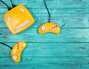 Two yellow joystick and game console on a blue wooden background. Video game console GamePad. Top view. Flat lay © alatielin