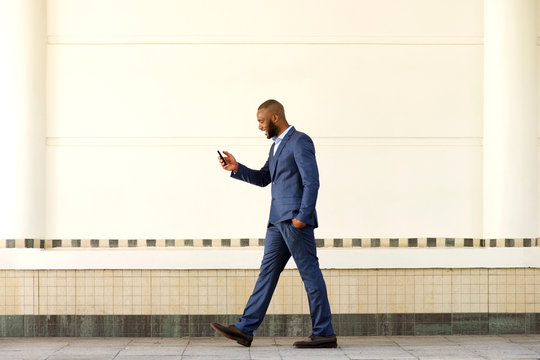 young businessman walking outdoors and using cell phone