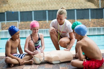 Lifeguard assisting children during rescue training - Powered by Adobe