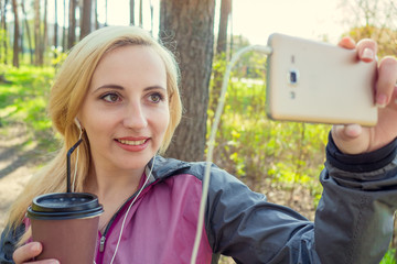 sporty girl holding a phone in hand and taking a selfie with a cocktail