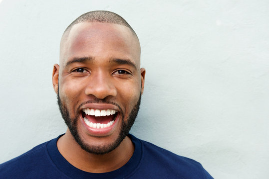 cheerful young african man laughing against white wall