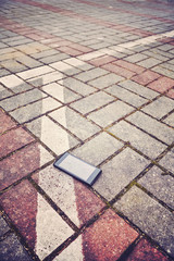 Fototapeta premium Vintage stylized picture of a mobile phone with broken screen on a parking pavement, selective focus.