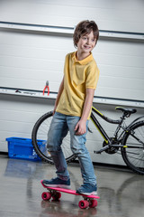 Fototapeta na wymiar Adorable boy with pink penny board, bicycle behind
