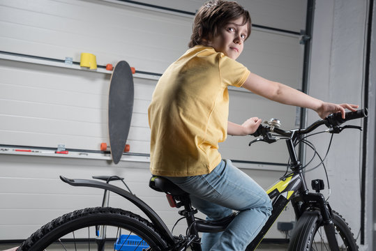 Cute Little Boy In T-shirt And Jeans Riding Bicycle