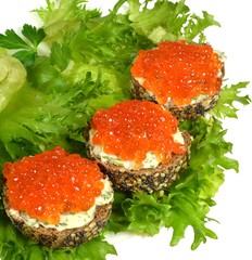 Small sandwiches of black baguette, sprinkled with grains of cereals and poppy, with red caviar and butter, shot down with finely chopped dill, lie on green leaves of crispy salad