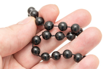 Black beads in hand on a white background
