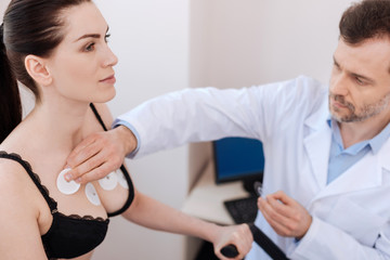 Fototapeta premium Careful medical worker applying sensors on womans chest
