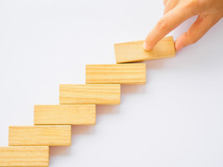 Concept of building success foundation. Women hand put wooden blocks in the shape of a staircase