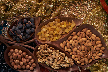 Obraz premium Large collection of nuts, seeds and dried fruits in brown wooden bowls isolated on a golden background