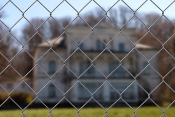 Fototapeta premium Close up of a wire fence with a building in the background - safety concept