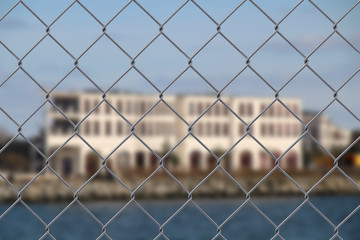 Close up of a wire fence with a  building in the background  - safety concept