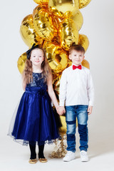 Boy and girl with balloons are standing in Studio on white background