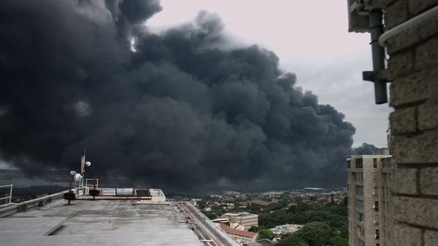 City Crisis Pollution: A Rooftop View of an Environmental Disaster Unleashing Thick Black Plumes of Toxic Smoke into the Atmosphere