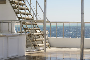 Boat ladder, Deck on the stern of the yacht on a bright sunny day and beautiful blue sea water.