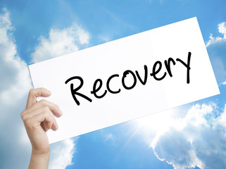  Recovery  Sign on white paper. Man Hand Holding Paper with text. Isolated on sky background