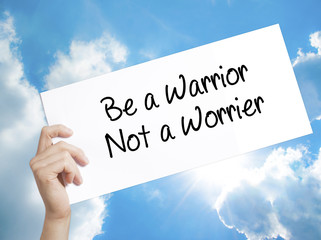Be a Warrior Not a Worrier Sign on white paper. Man Hand Holding Paper with text. Isolated on sky background