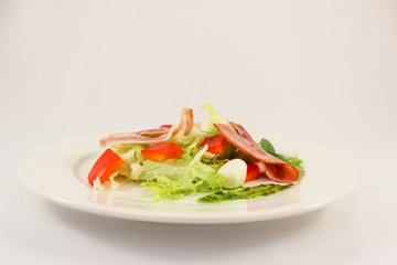 Salad from leaves of an iceberg, bacon, quail eggs, sweet pepper, dressed with pesto sauce