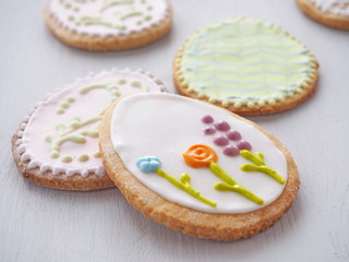 Easter sugar cookies with floral ornament. Homemade cookies glazed with royal icing. Ester treat upon rustic table. Beautiful biscuits in the shape of easter egg. Selective focus.