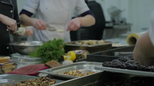 Mixed ethnicity team of professional chefs preparing and cooking food in a commercial kitchen. In slow motion.