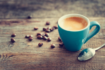 Espresso coffee cup with beans on wooden board. Retro stylized.