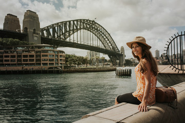 Smiling woman sitting in Sydney in front of Harbour Bridge.
