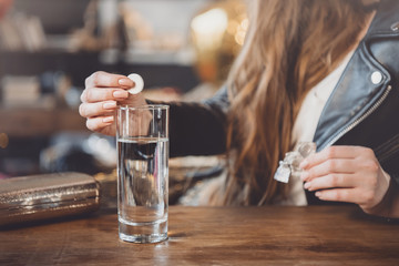 woman with hangover with medicines in messy room after party