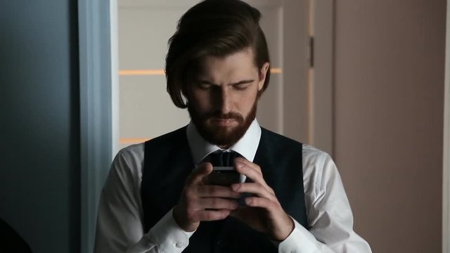 Bearded handsom young man with stylish well-trimmed using his smartphone.