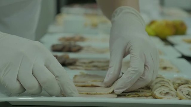 Close up on hands holding a brisket on a white dish, quickly slicing cooked meat. Slow motion