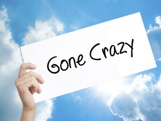 Gone Crazy  Sign on white paper. Man Hand Holding Paper with text. Isolated on sky background