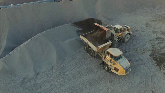 excavator loading granite or ore into dump truck at opencast, top viewe