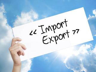 Import - Export Sign on white paper. Man Hand Holding Paper with text. Isolated on sky background.