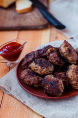 Beef cutlets in a ceramic plate on a rough village napkin. Meatballs on the wooden table.