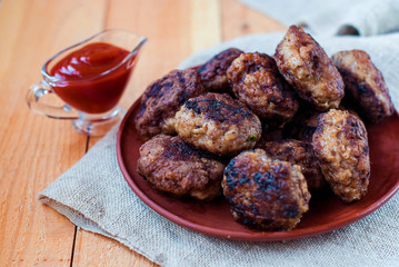 Beef cutlets in a ceramic plate on a rough village napkin. Meatballs on the wooden table.