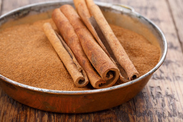 Cinnamon sticks and powder on wooden table.