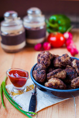 Beef cutlets with sauce and vegetables. Meatballs with ketchup and green onions. Meatballs on a rough wooden table in a rustic style.
