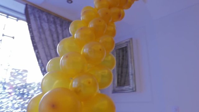 The design of a hall in the yellow balloons. Bunch of colored balloon decoration. Yellow background. Steadicam shot.