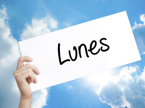 Lunes (Monday in Spanish) Sign on white paper. Man Hand Holding Paper with text. Isolated on sky background