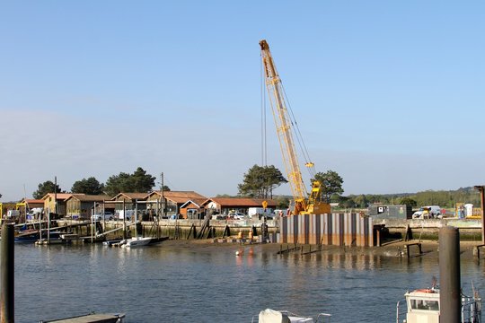 grue enfon&ccedil;ant des palplanches en m&eacute;tal dans la vase du port  par vibration