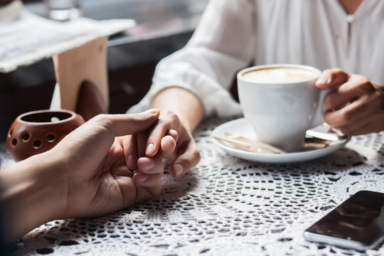 Young couple holding hands at the cafe, closeup