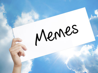 Memes Sign on white paper. Man Hand Holding Paper with text. Isolated on sky background.