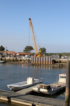 grue enfon&ccedil;ant des palplanches en m&eacute;tal dans la vase du port  par vibration