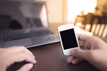 Young man working at home using smart phone and laptop computer