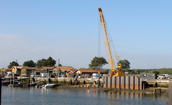 grue enfon&ccedil;ant des palplanches en m&eacute;tal dans la vase du port  par vibration