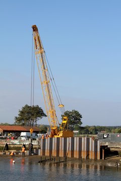 grue enfon&ccedil;ant des palplanches en m&eacute;tal dans la vase du port  par vibration