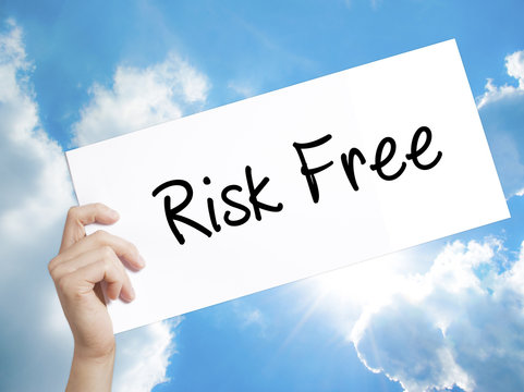 Risk Free Sign on white paper. Man Hand Holding Paper with text. Isolated on sky background