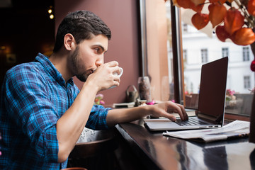 young man working on his computer at the cafe