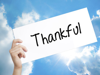 Thankful  Sign on white paper. Man Hand Holding Paper with text. Isolated on sky background